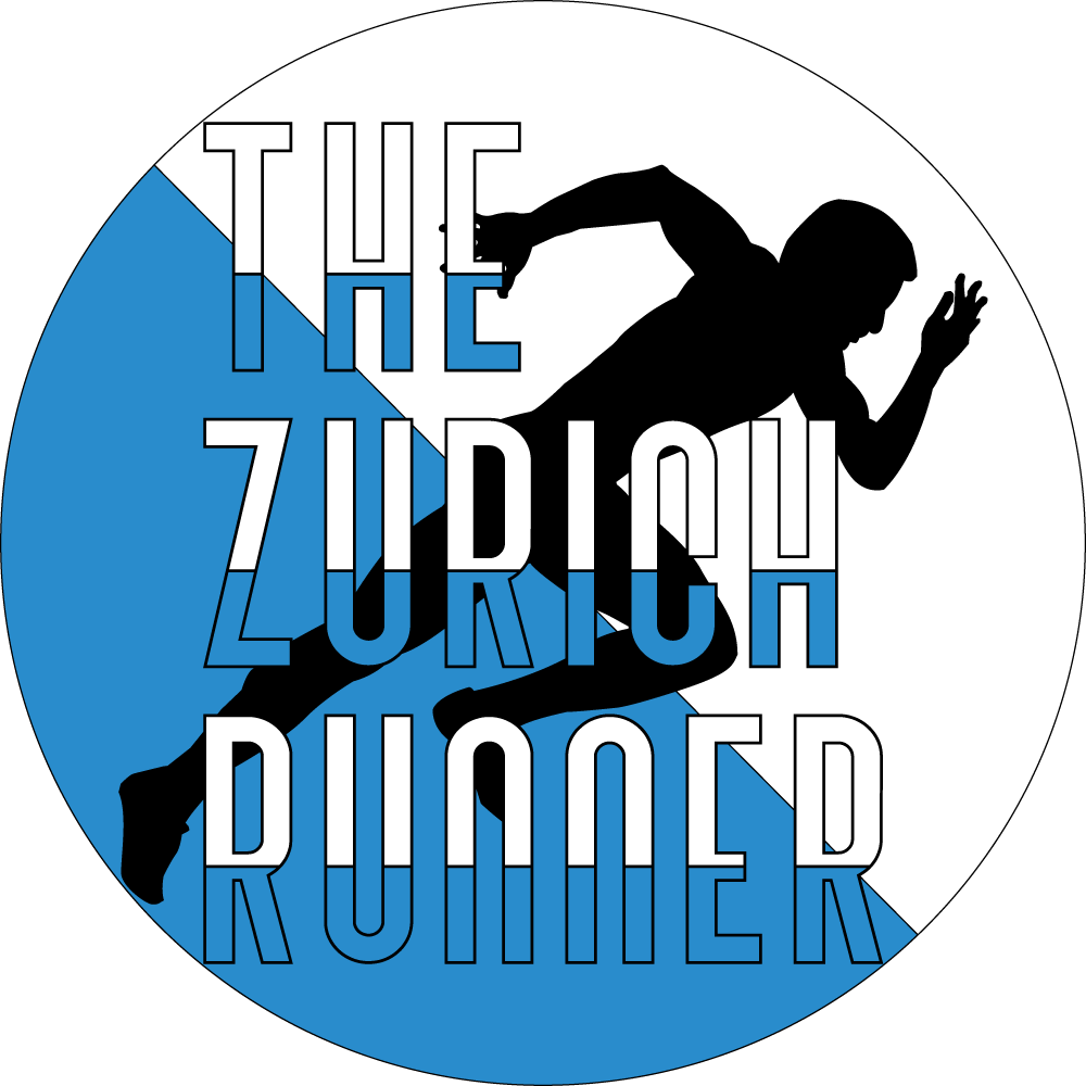 Round logo with the black silhouette of a runner in the background. The words "The Zurich Runner" are visible on top of the silhouette in white and blue letters.